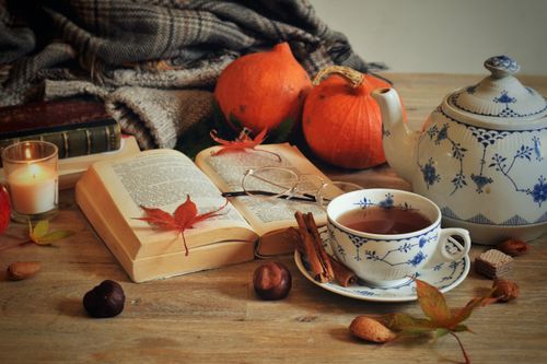 Free Cozy autumn scene with a teapot, books, and pumpkins in warm tones. Stock Photo