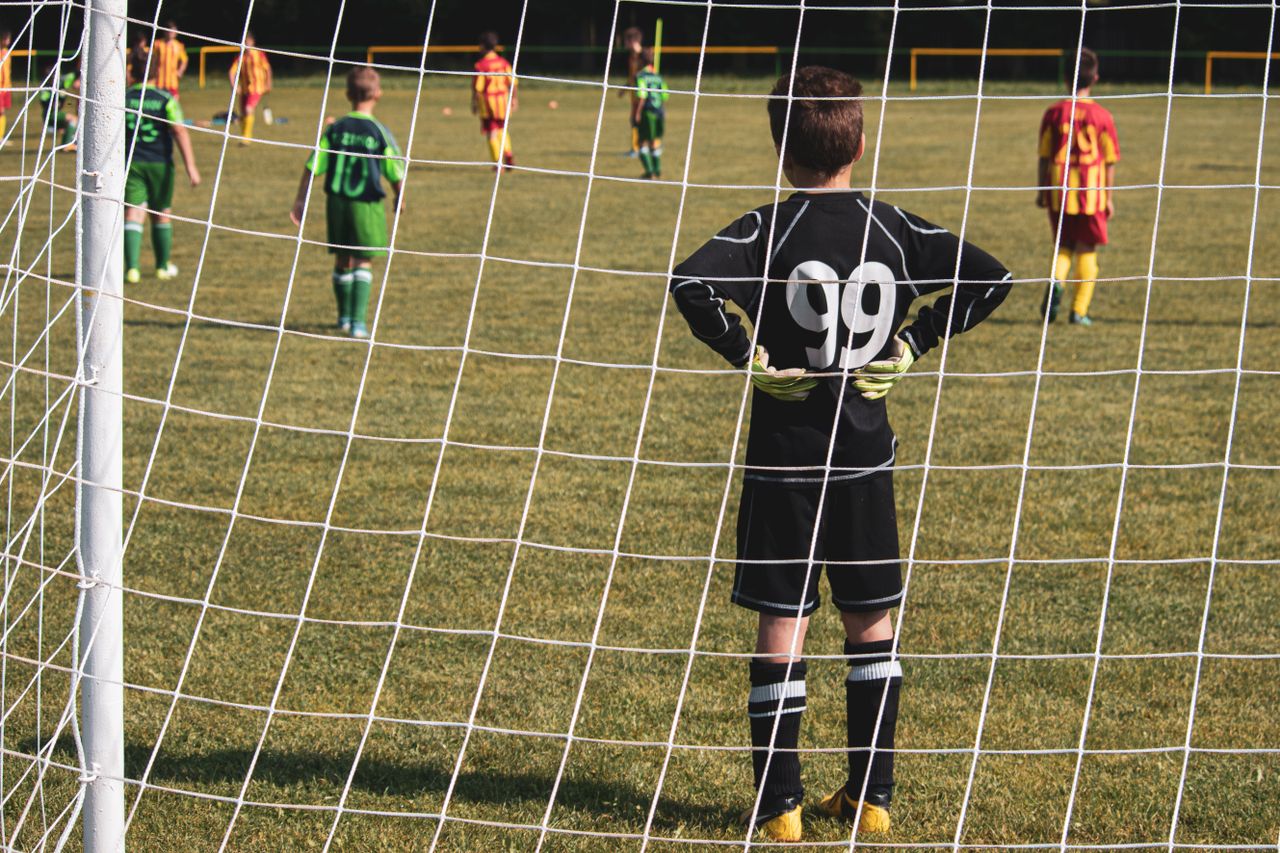 a young goalkeeper stands ready while teammates prepare for the soccer