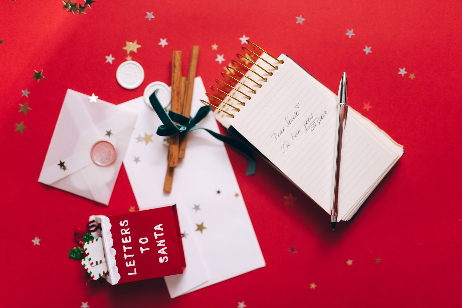 Christmas flat lay with a letter to Santa, cinnamon sticks, ornaments, and holiday decorations.