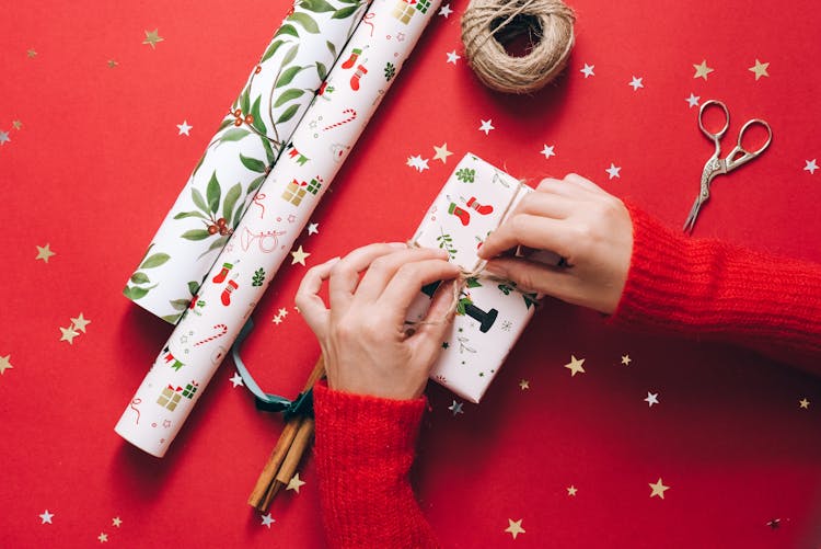 A Person Tying A String On A Present