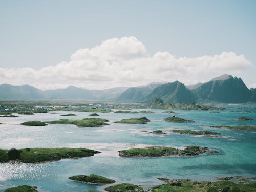 Body of Water Near Mountain Range Under Clear Sky