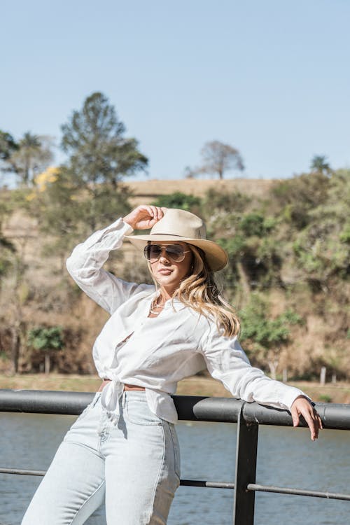 Woman in White Long Sleeve Shirt Leaning on Metal Railings