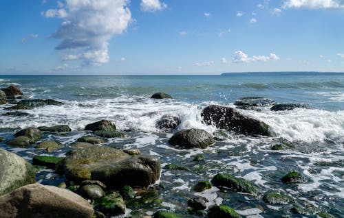 Free Rocky Shore Under Blue Sky and White Clouds Stock Photo