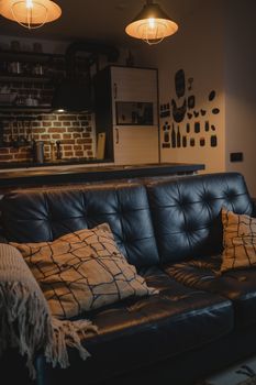 A cozy leather couch adorned with throw pillows in a modern industrial interior setting.