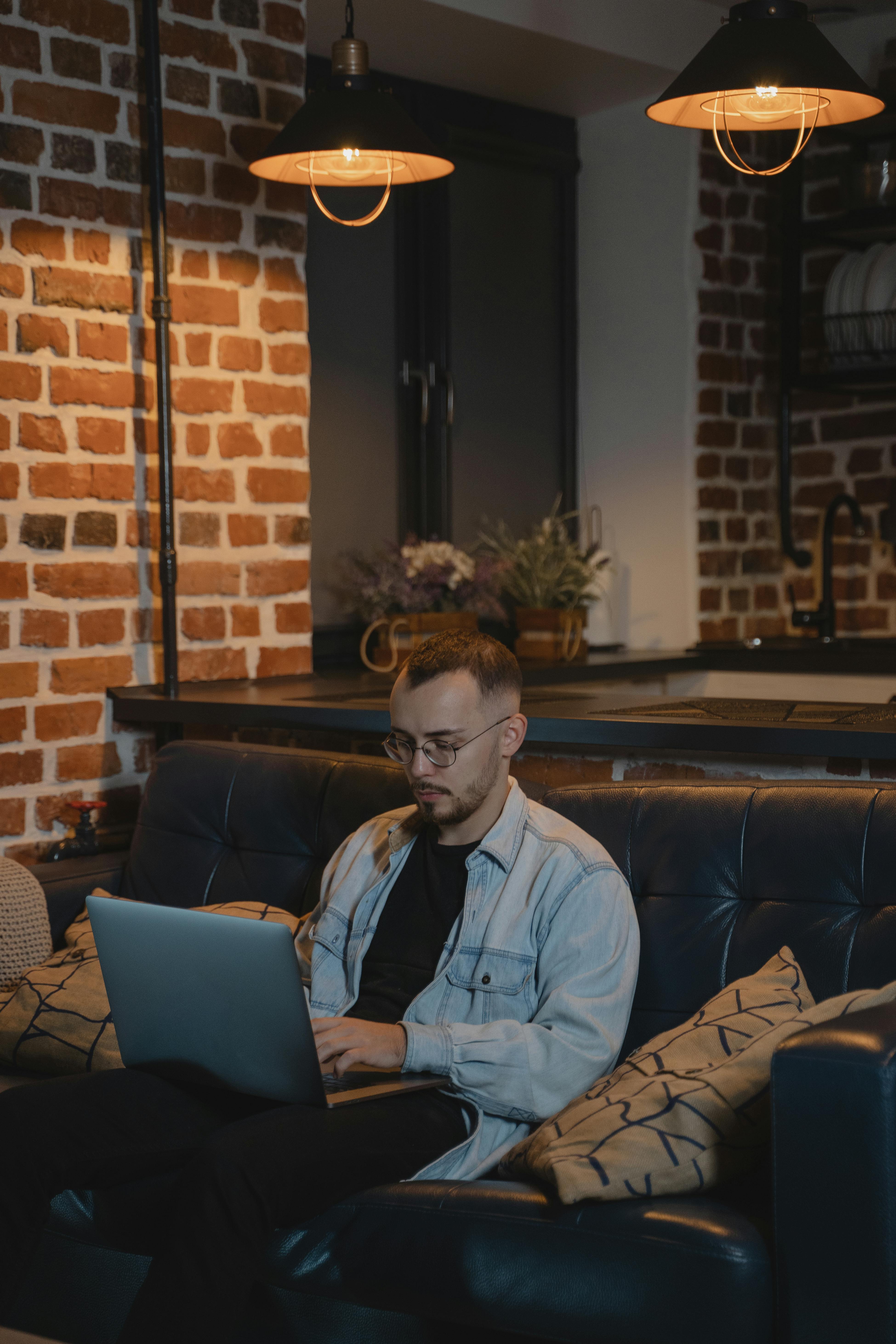 Man with Serious Face Sitting on a Couch Using his Laptop · Free Stock Photo