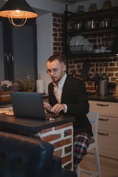 Caucasian man working remotely on a laptop in a cozy kitchen setting.
