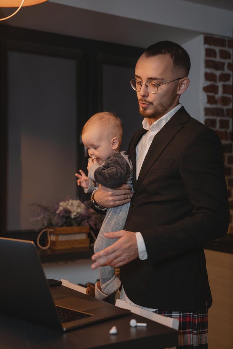 A Man Working From Home While Carrying A Baby