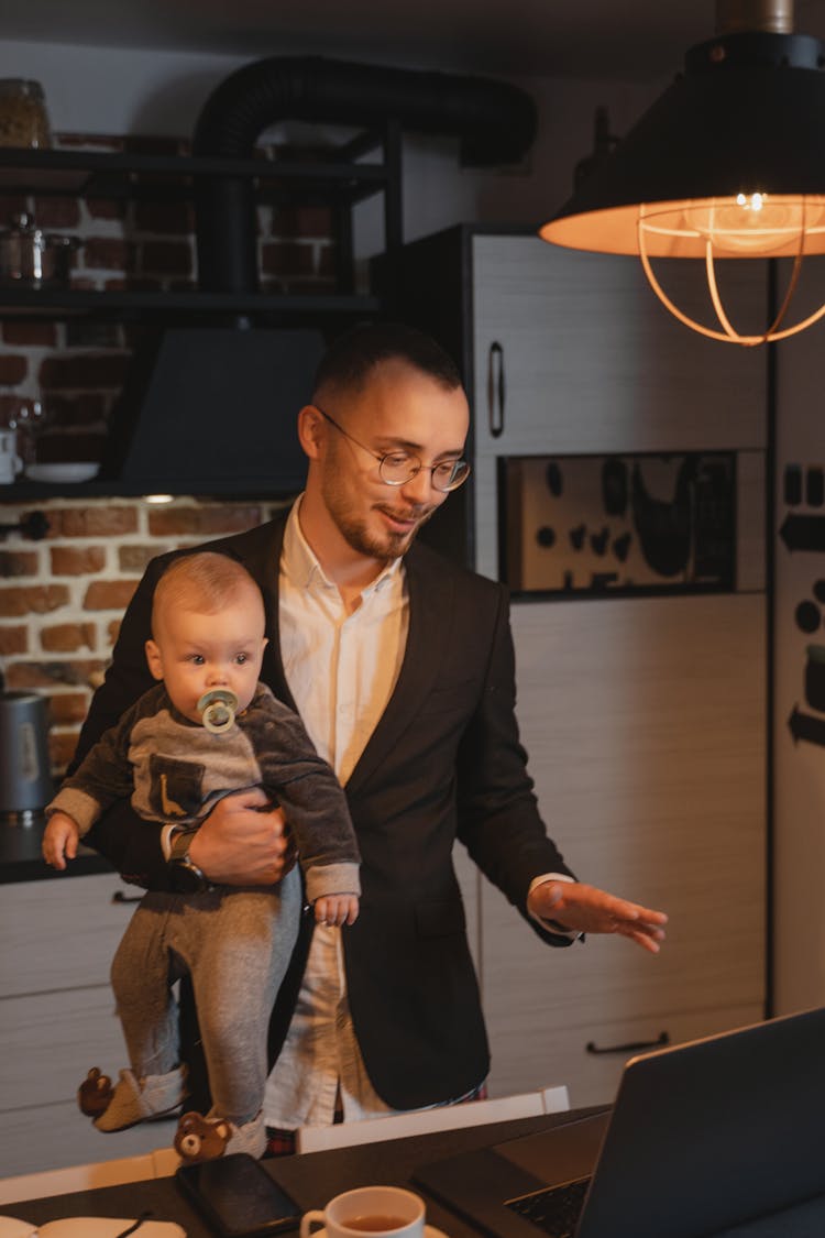 A Man Working From Home While Carrying A Baby