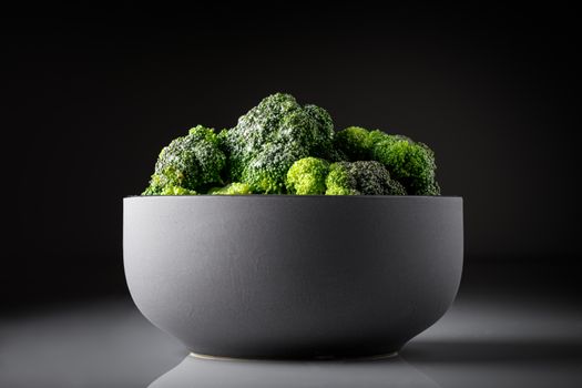 Close-up of fresh broccoli in a stylish black bowl against a dark background.