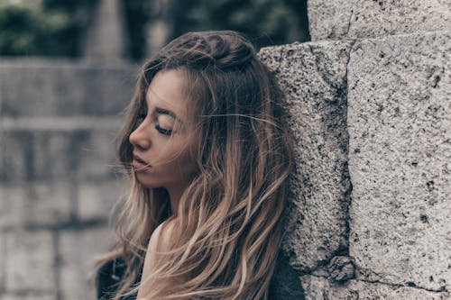 Photo of a Woman Leaning on a Rough Surface