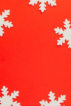 A captivating image of white snowflakes on a bright red backdrop, perfect for holiday themes.