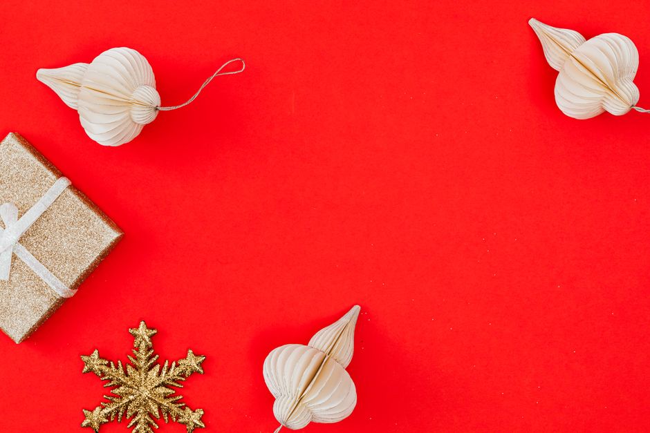 Elegant Christmas ornaments and gift on a vibrant red background, perfect for holiday themes.