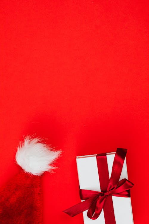 A Present and a Santa Hat on a Red Surface 