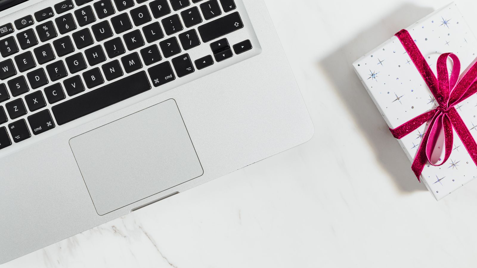 A wrapped gift with a red ribbon beside a laptop