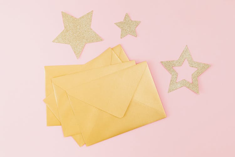 Yellow Envelopes And Gold Stars Against Pink Background