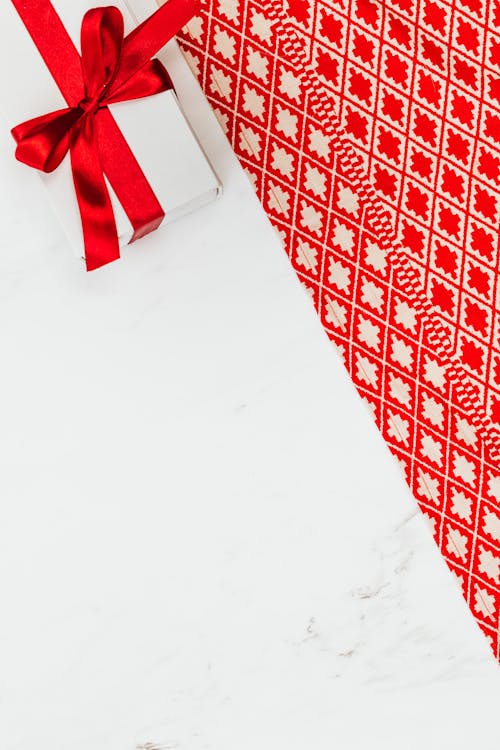 Christmas Gift in a White Box with Red Ribbon and Christmas Wrapping Paper 