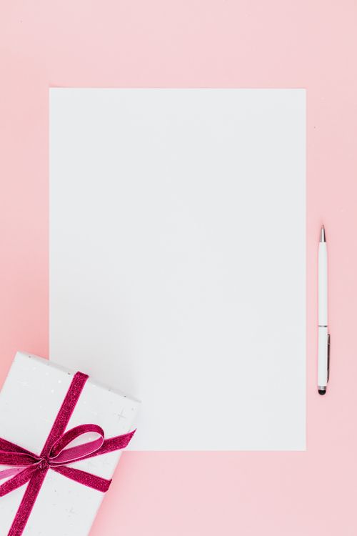 Free Gift box with ribbon and blank paper on a pink surface, ideal for festive and creative concepts. Stock Photo