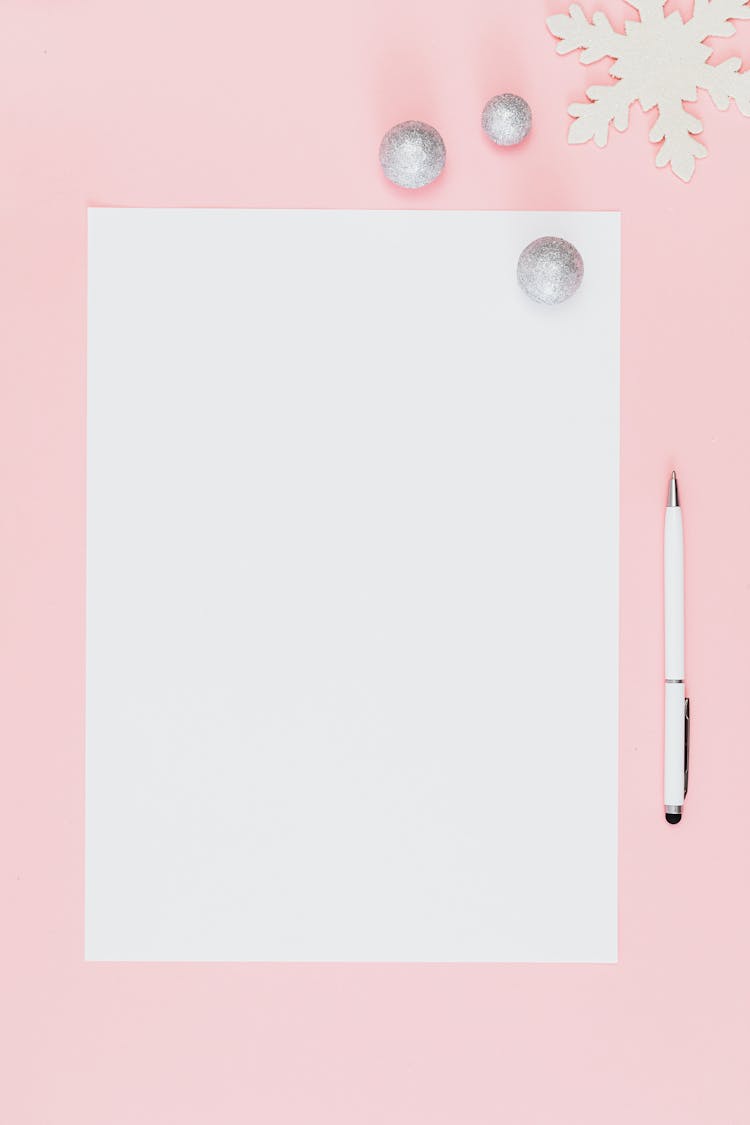 Close-Up Shot Of A White Bond Paper And A Pen On A Pink Surface