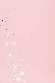 Soft pink pastel background with scattered star-shaped confetti, perfect for festive designs.