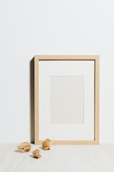 Simple wooden frame against white wall with shadows, artistic minimalism
