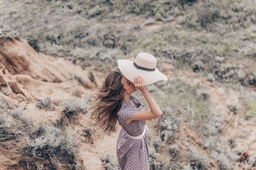 Woman Standing on Grass Field Holding a Sun Hat 