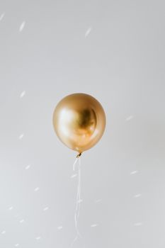 一个金色气球漂浮着白色丝带，背景是浅色的