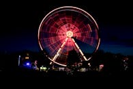 长曝光镜头捕捉了夜间游乐园里旋转的照明摩天轮的壮观景象