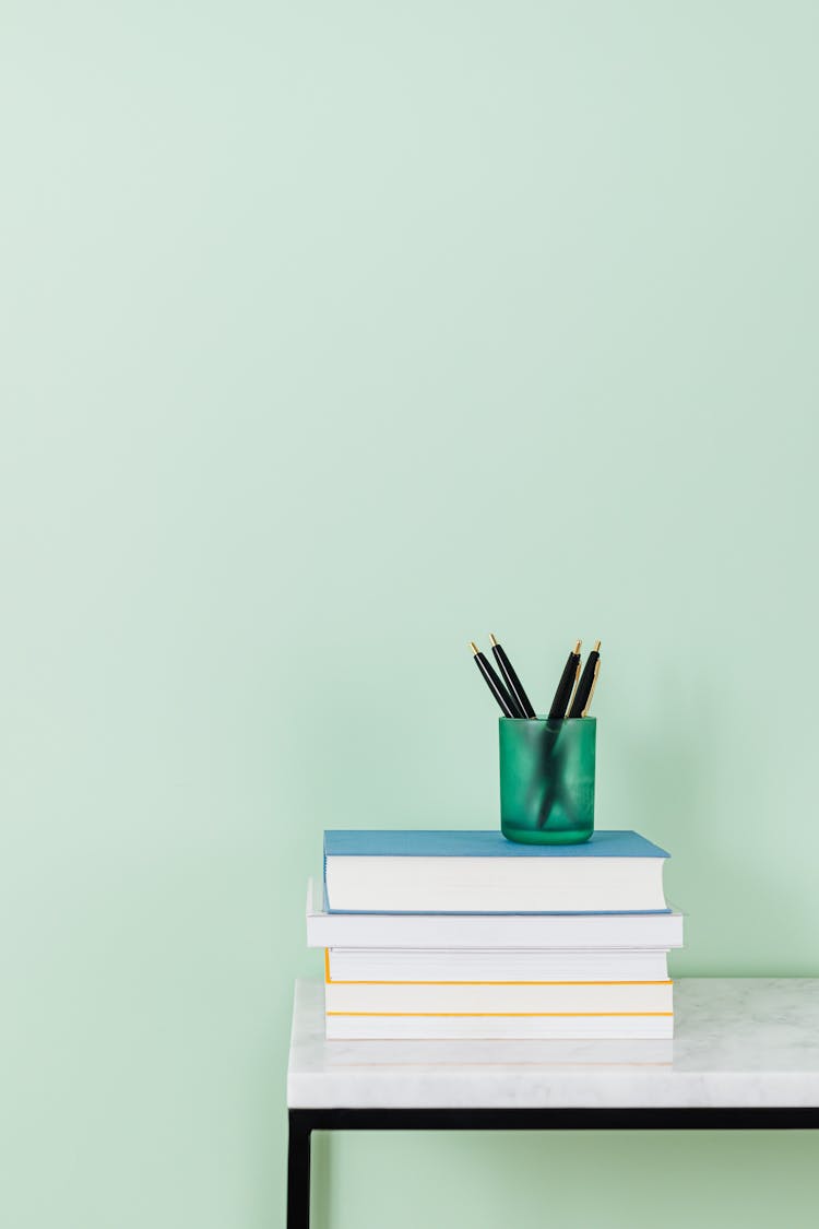 Pens In Cup On Stack Of Books