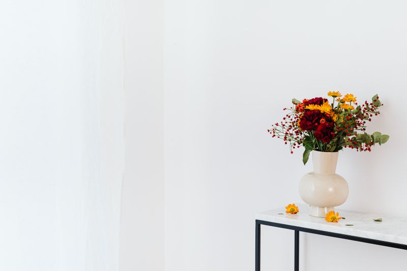 Flower arrangement in a ceramic vase on a console table, photo by Kaboompics.com on Pexels