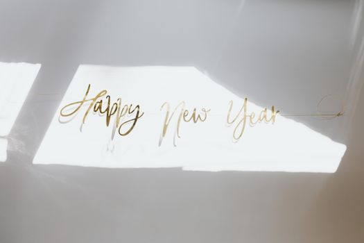 白色背景上，优雅的“新年快乐”文字沐浴在自然阳光下