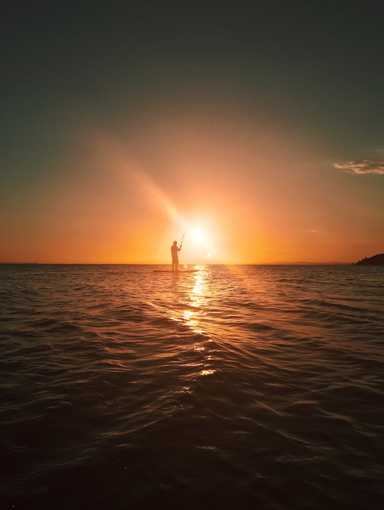 Person On Paddleboard Floating In Sunset