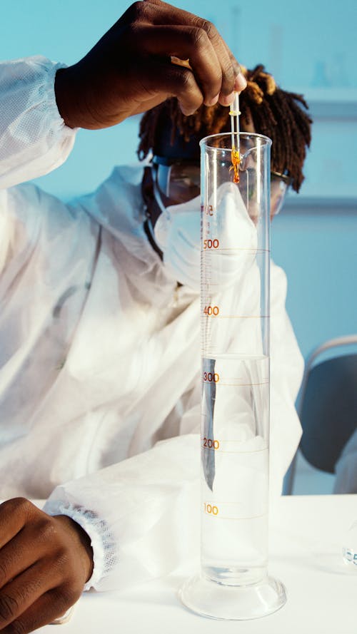 A Man Doing an Experiment by Using a Graduated Cylinder