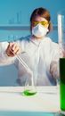一名女科学家穿着防护装备，在实验室里使用试管