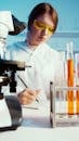 A Woman Writing on Her Notebook While Doing an Experiment