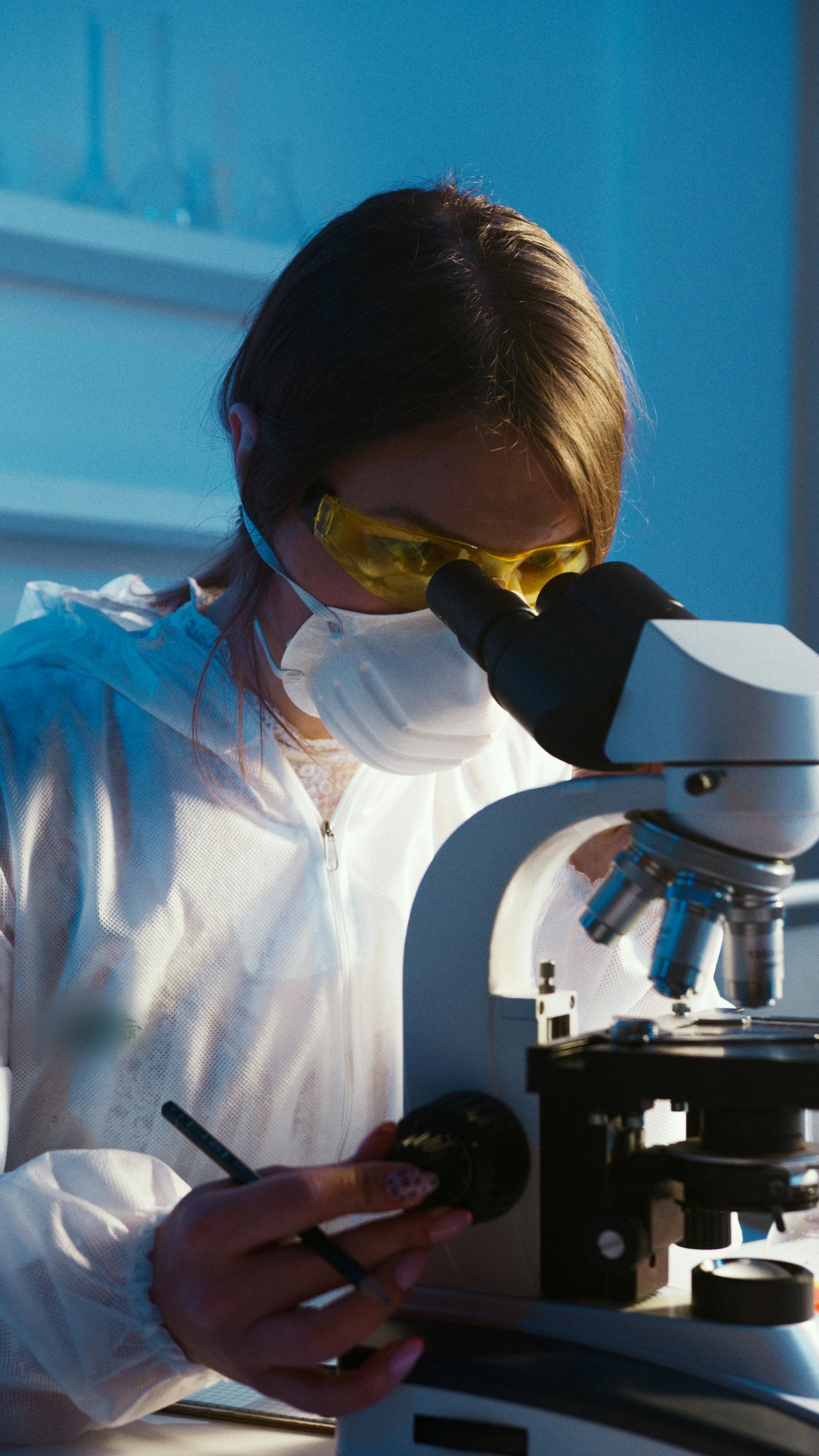 photo of woman looking through microscope