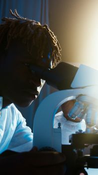 在温暖的灯光下，一位专注的科学家正在实验室里使用显微镜