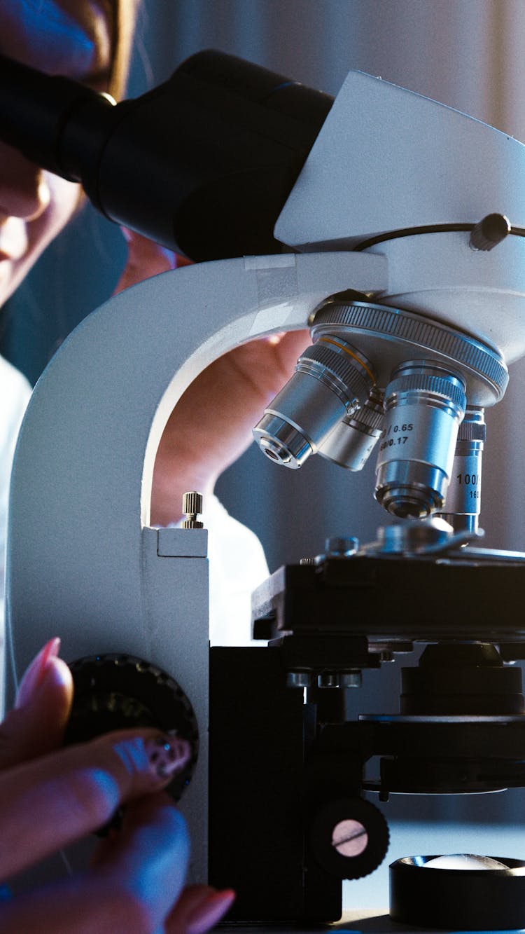 Close-Up View Of A Person Looking Through The Microscope