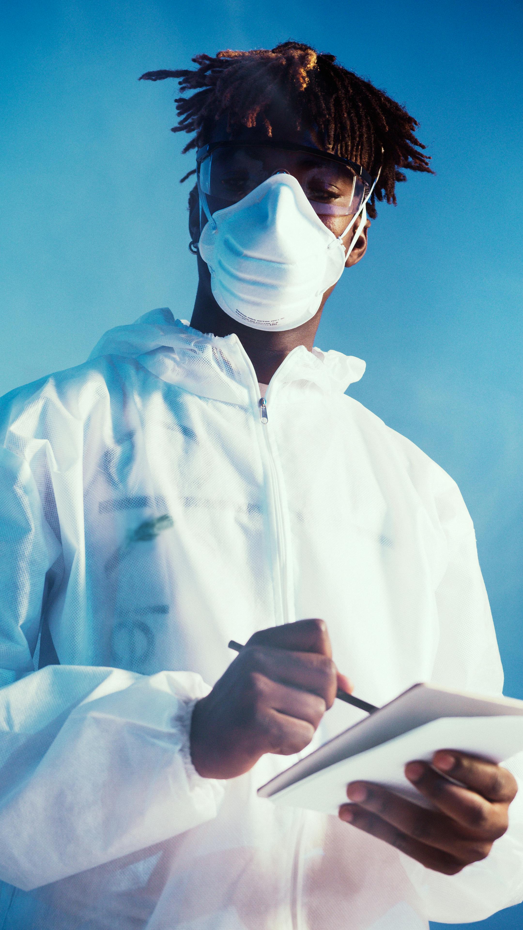a man wearing a face mask and notebook while looking at the camera