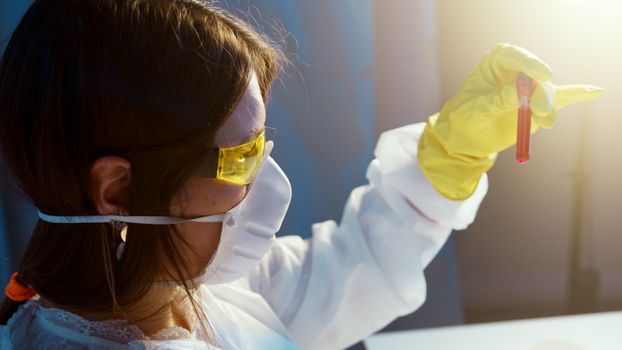一名女科学家身着防护装备，在实验室里检查血液样本