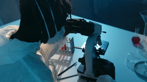 A Man Looking at the Camera While Holding the Eyepiece of the Microscope