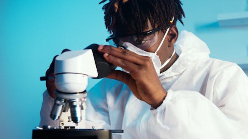 A Man Looking at the Camera While Holding the Eyepiece of the Microscope