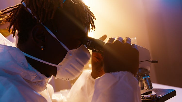 A Man Looking Through The Microscope