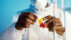 科学家穿着实验室服装，正在处理用于研究的测试样本