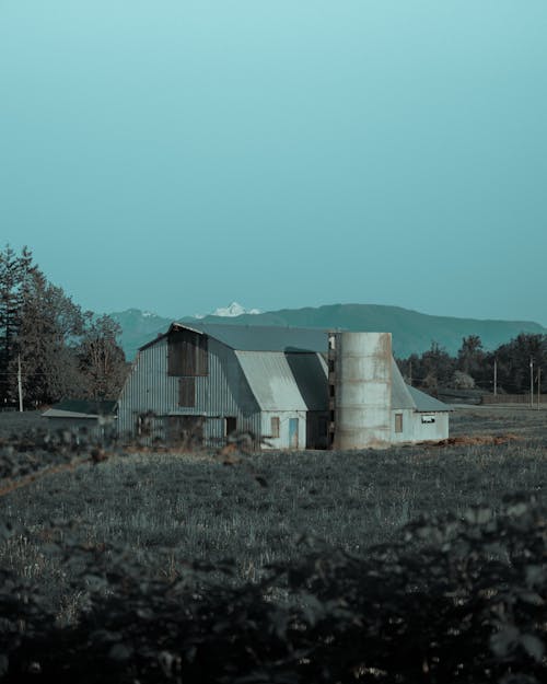 A Barn With Silo On Farmland Under Clear Sky