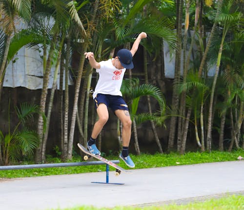 Free Young Man in White T-shirt and Black Shorts Doing Skateboard Stunts Stock Photo