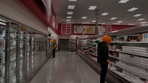 Two People Shopping In A Supermarket With Pumpkin On Their Head