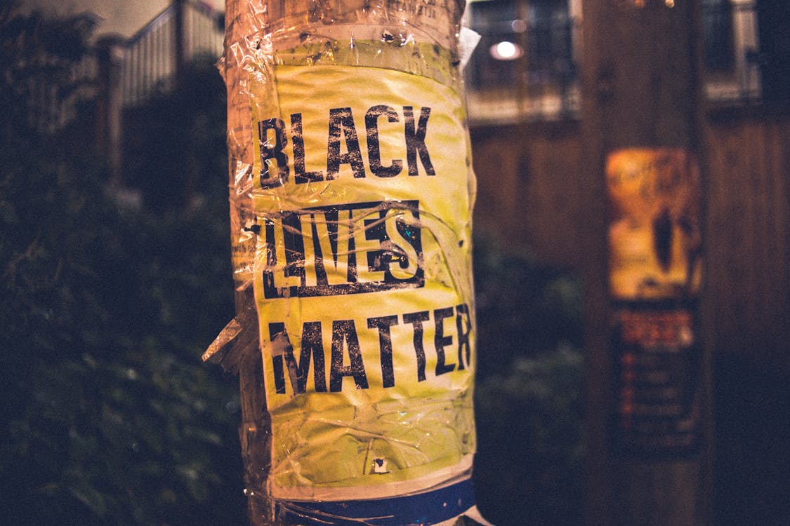 Inscription of protest movement saying black lives matter on pole in city street in evening