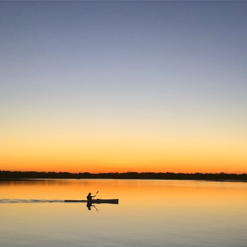gratis Silhouet Van Man Binnenkant Van Boot Zeilen Op Waterlichaam Tijdens Zonsondergang Stockfoto