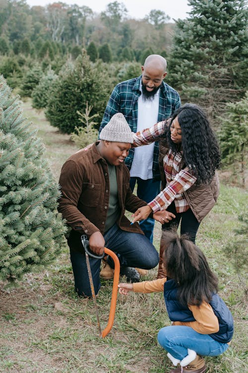 Black positive family preparing for sawing Christmas tree