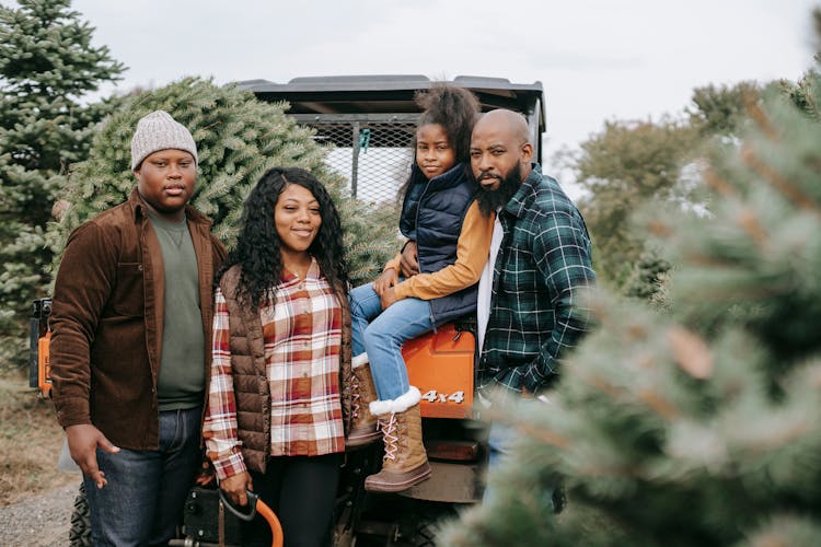 Happy Black Family Near Firs In Countryside